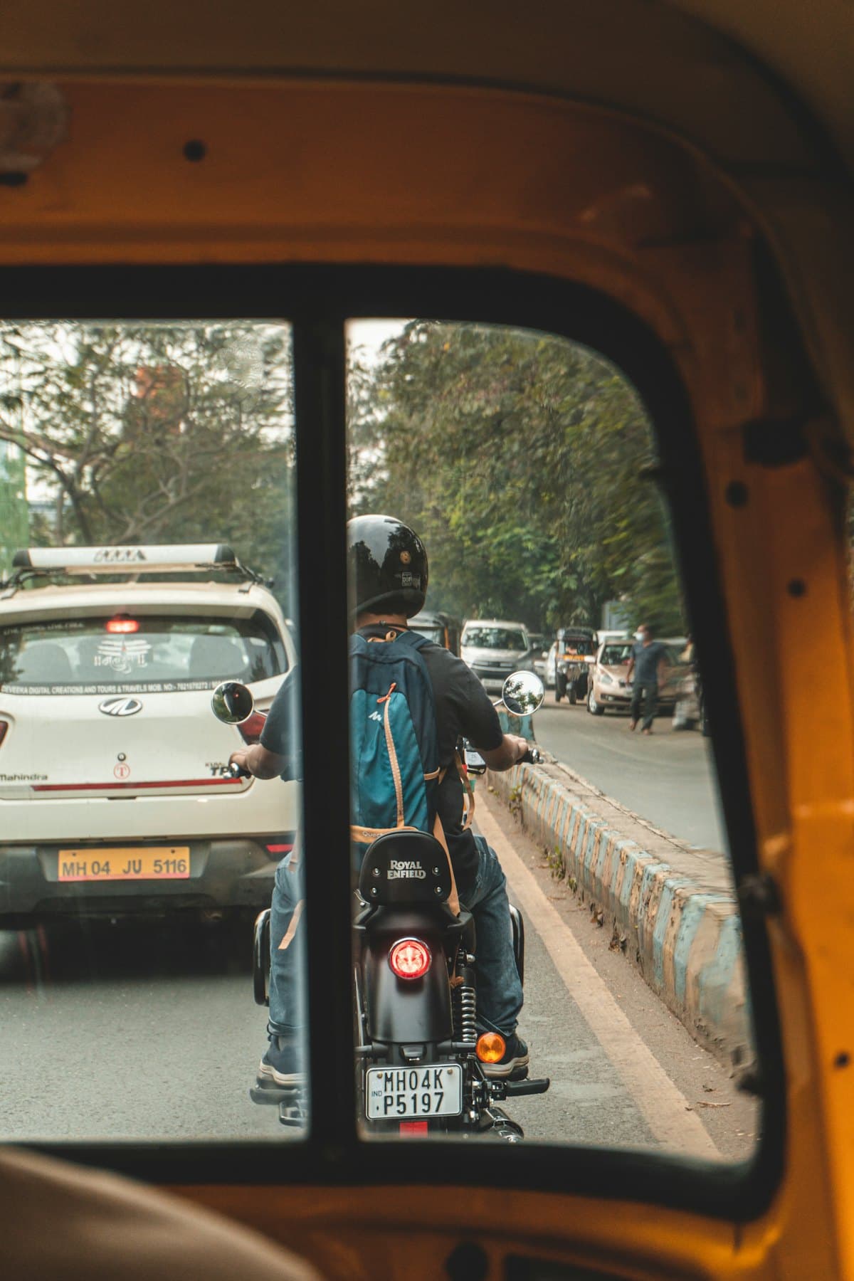 The road ahead seen from the back seat of an auto-rickshaw, a motorbike rider in front